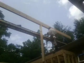 Carpenter setting a ridge beam over a new addition frame — Ice Dam Removal by Roofing Brothers in Amma