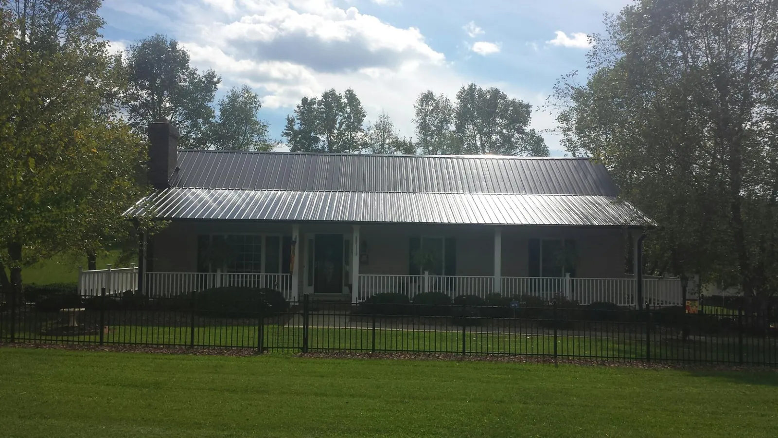 Gray metal roof on a brick ranch with a full width front porch — Gutter Guard Installation work by our crew in Amma