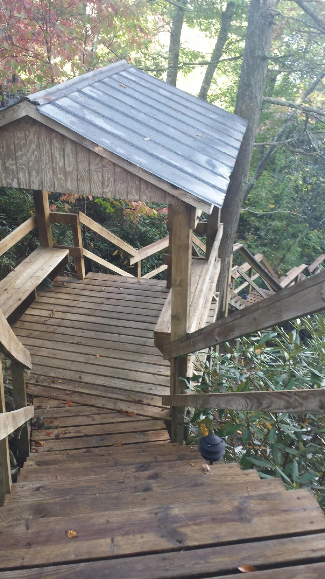 Metal roofed shelter over wooden steps on a wooded walkway — Skylight Repair & Installation work by our crew in Amma