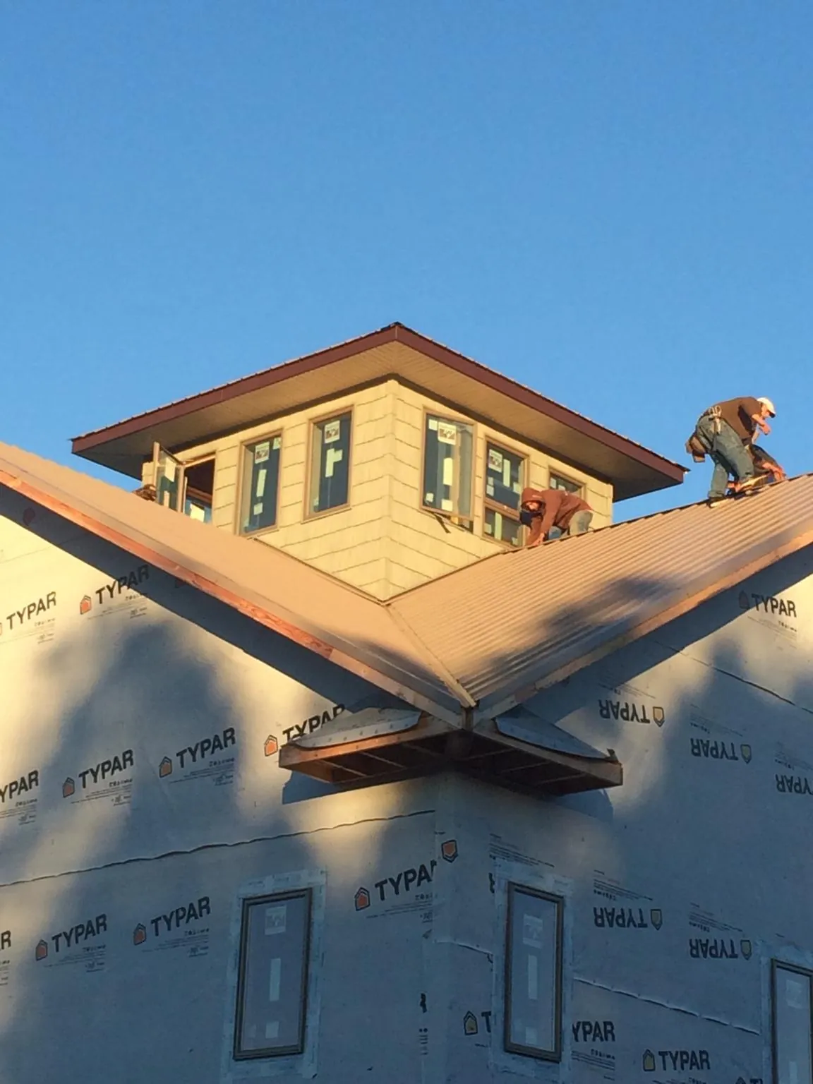 Roofers working around a rooftop cupola on a new metal roof at sunset — Roof Waterproofing in Amma by Roofing Brothers